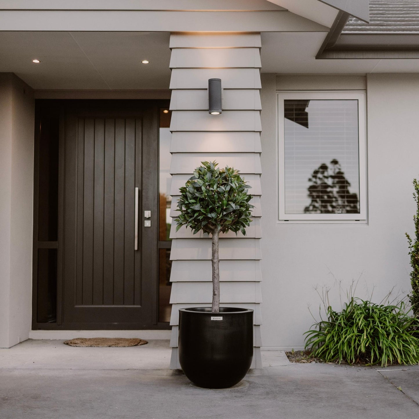 A black Modscene planter in front of a house pillar.