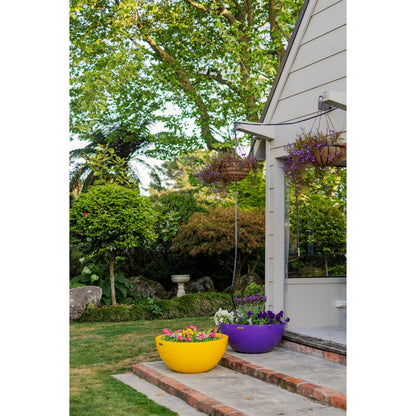 Yellow and purple planter bowls plated with beautiful flowers sitting on a stone steps.